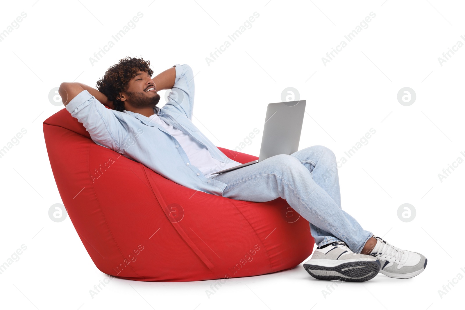 Photo of Smiling man with laptop sitting on beanbag chair against white background