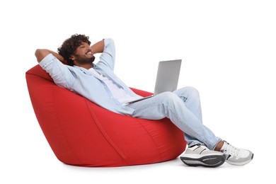 Photo of Smiling man with laptop sitting on beanbag chair against white background