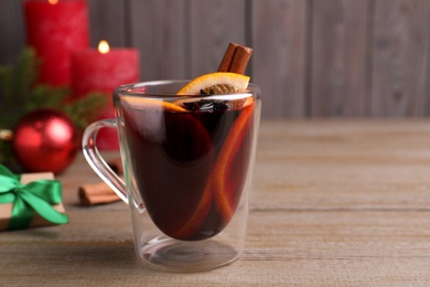 Photo of Glass cup of aromatic mulled wine on wooden table