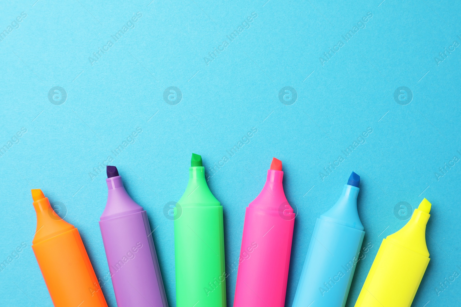 Photo of Bright markers on light blue background, flat lay. Space for text