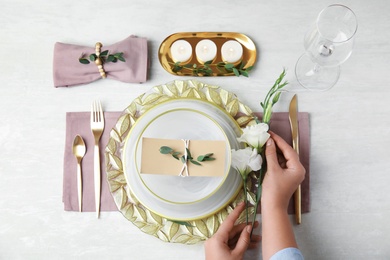 Woman setting table for festive dinner, top view