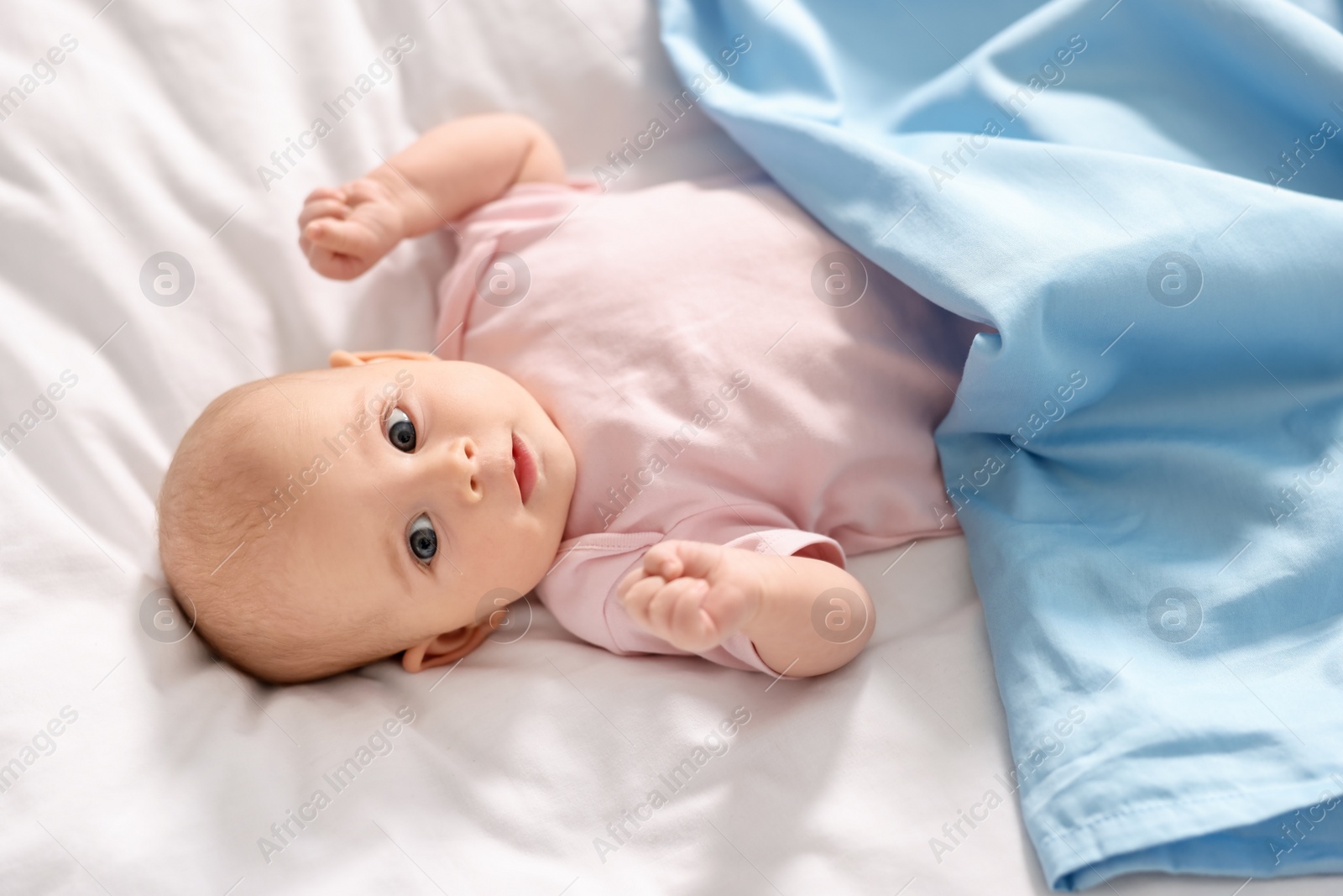 Photo of Cute little baby lying on white sheets