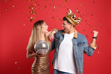 Photo of Happy couple with disco ball and confetti on red background