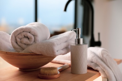 Photo of Clean towels, soap dispenser and shower brush in bathroom