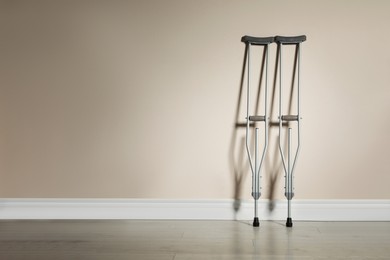 Photo of Pair of axillary crutches near color wall. Space for text