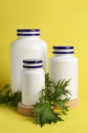 Photo of Medicine bottles and green leaf on yellow background