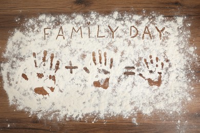Photo of Phrase Family Day and handprints on flour scattered over wooden table, top view