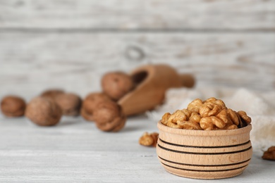 Photo of Bowl with tasty walnuts on wooden table. Space for text