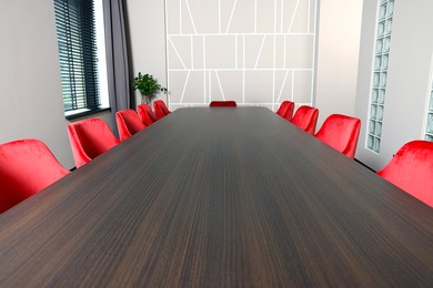 Photo of Empty conference room with stylish red office chairs and large wooden table