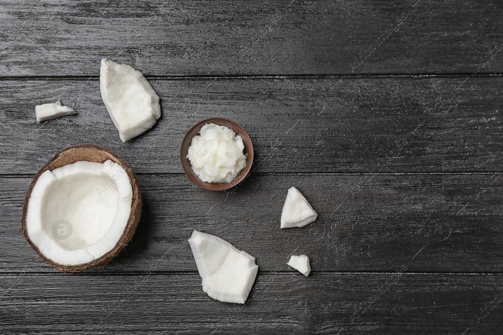 Photo of Ripe coconut and oil in bowl on wooden table, top view. Healthy cooking