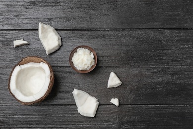 Ripe coconut and oil in bowl on wooden table, top view. Healthy cooking