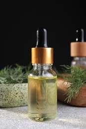 Photo of Bottle of essential oil and fresh dill on light grey table