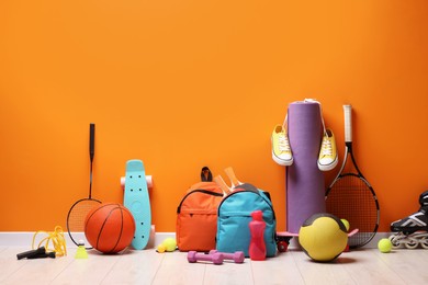 Many different sports equipment near orange wall indoors