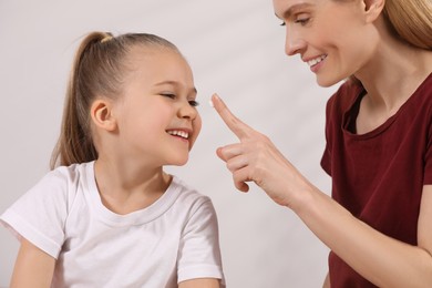 Photo of Mother applying ointment onto her daughter's nose on white background