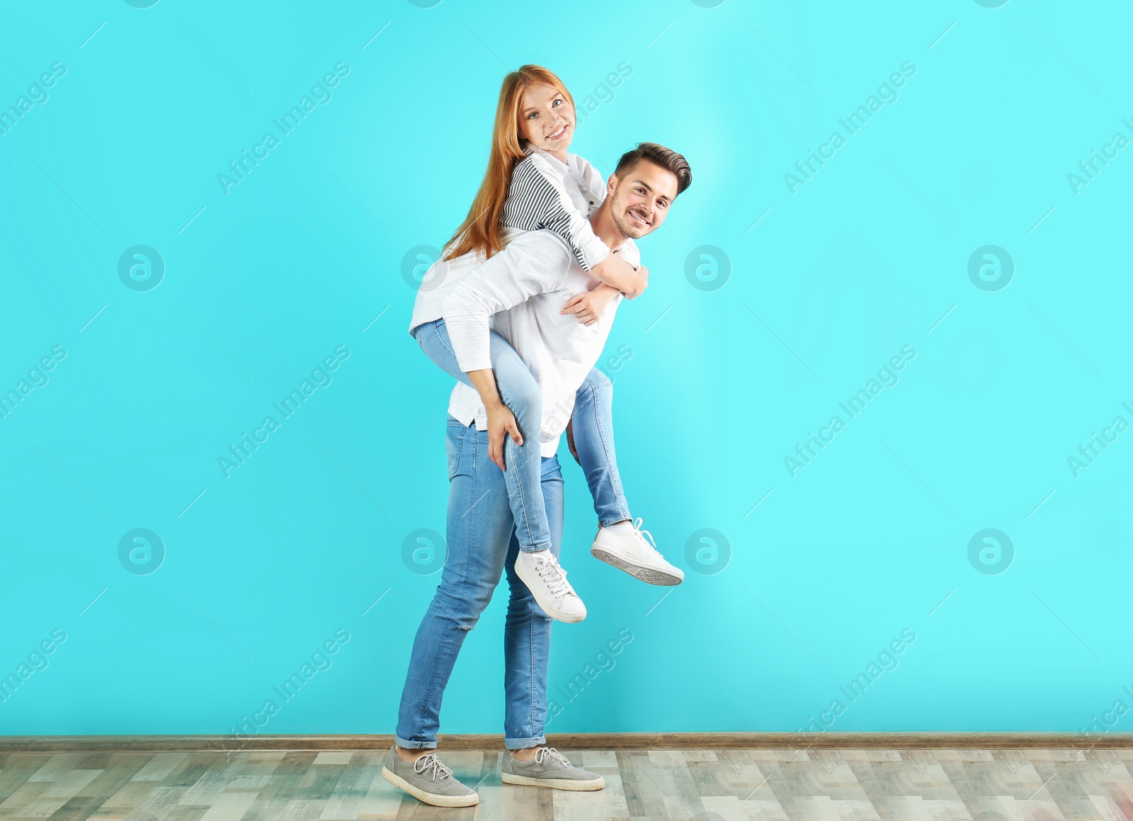 Photo of Young couple in stylish jeans near color wall