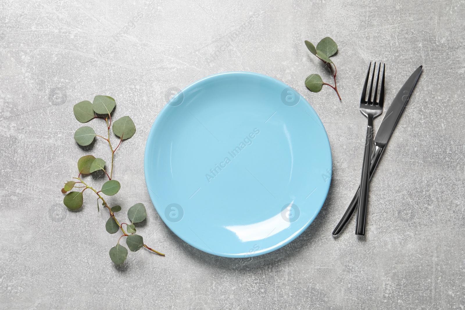 Photo of Stylish table setting with cutlery and eucalyptus leaves, flat lay