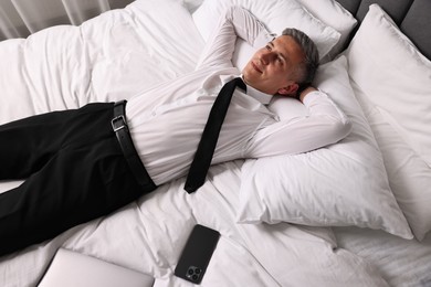 Photo of Businessman in office wear resting on bed indoors, above view