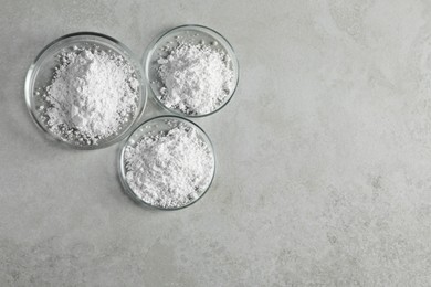 Photo of Petri dishes with calcium carbonate powder on light grey table, flat lay. Space for text