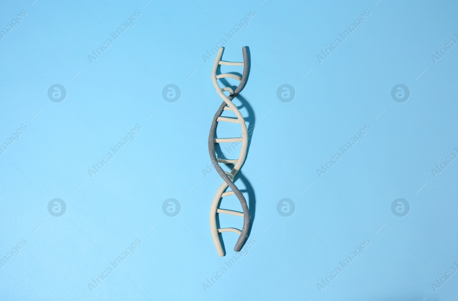 Photo of DNA molecule model made of colorful plasticine on light blue background, top view