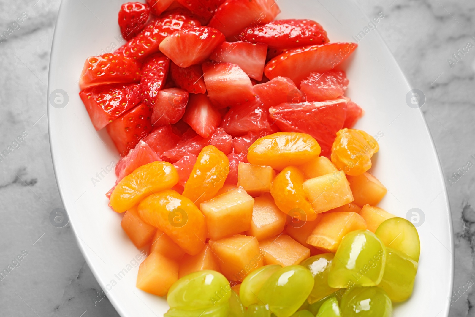 Photo of Plate with fresh cut fruits on table, closeup