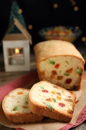 Photo of Delicious cake with candied fruits and Christmas decor on table, closeup