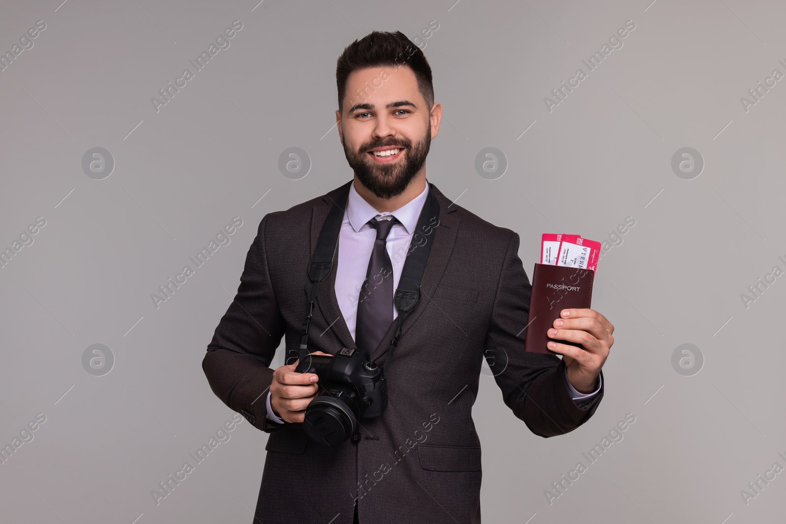 Photo of Happy businessman with passport, tickets and camera on grey background