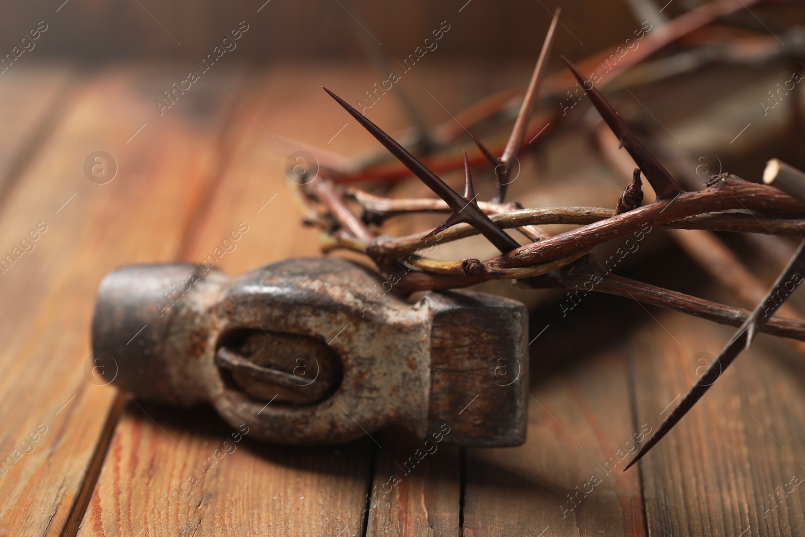 Photo of Crown of thorns and hammer on wooden table, closeup. Easter attributes