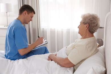 Caregiver examining senior woman in bedroom. Home health care service