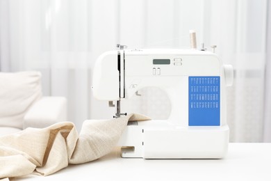 Photo of Sewing machine and fabric on white table in workshop