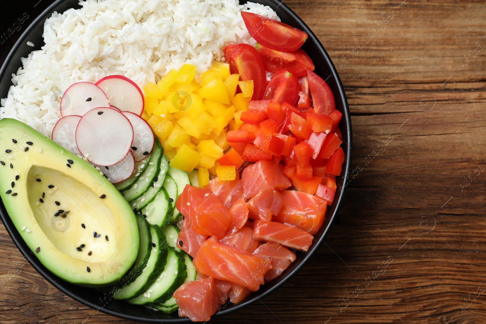 Photo of Delicious poke bowl with salmon and vegetables on wooden table, top view