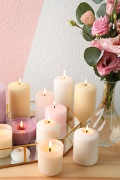 Set of burning candles on table against color background