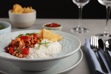Photo of Tasty chili con carne served with rice on gray table. Dinner in restaurant
