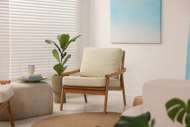 Photo of Comfortable beige armchair, ottoman and houseplant in living room. Interior design