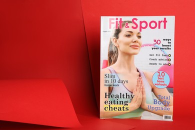 Photo of Modern printed sports magazine on red background, space for text