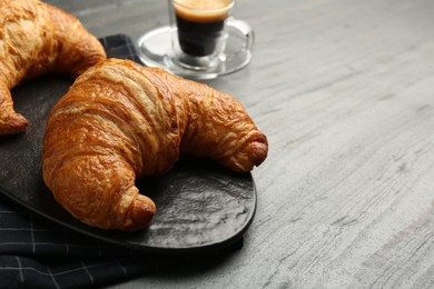 Photo of Delicious fresh croissants on gray table, closeup. Space for text