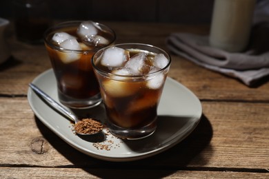 Photo of Refreshing iced coffee in glasses, ingredients and spoon on wooden table, closeup