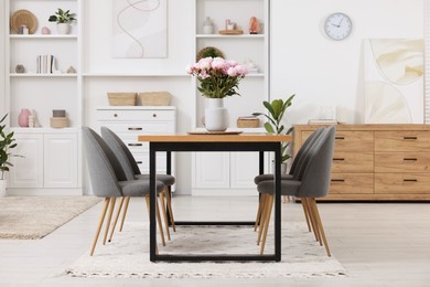 Photo of Stylish dining room with cosy furniture and flowers