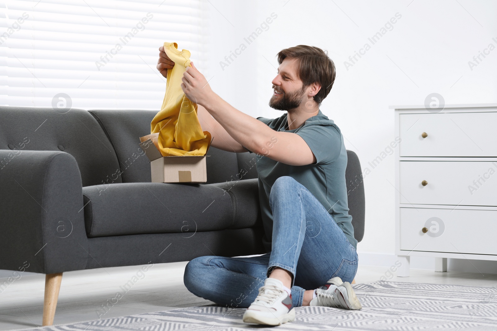 Photo of Happy man with parcel at home. Internet shopping