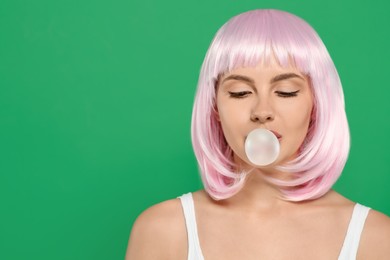 Photo of Beautiful woman blowing bubble gum on green background, space for text