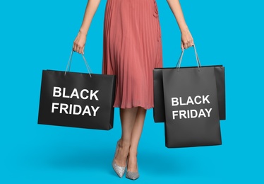 Woman with shopping bags on light blue background, closeup. Black Friday