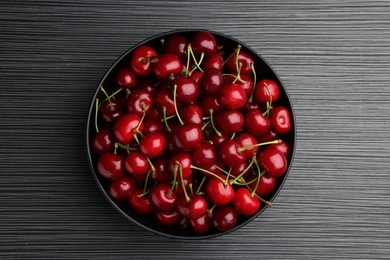 Photo of Bowl with ripe sweet cherries on dark wooden table, top view
