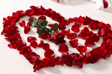 Photo of Honeymoon. Heart made with rose and beautiful petals on bed