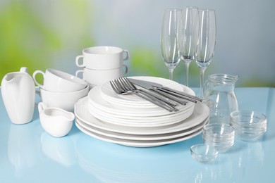 Set of clean dishes, glasses and cutlery on light blue table