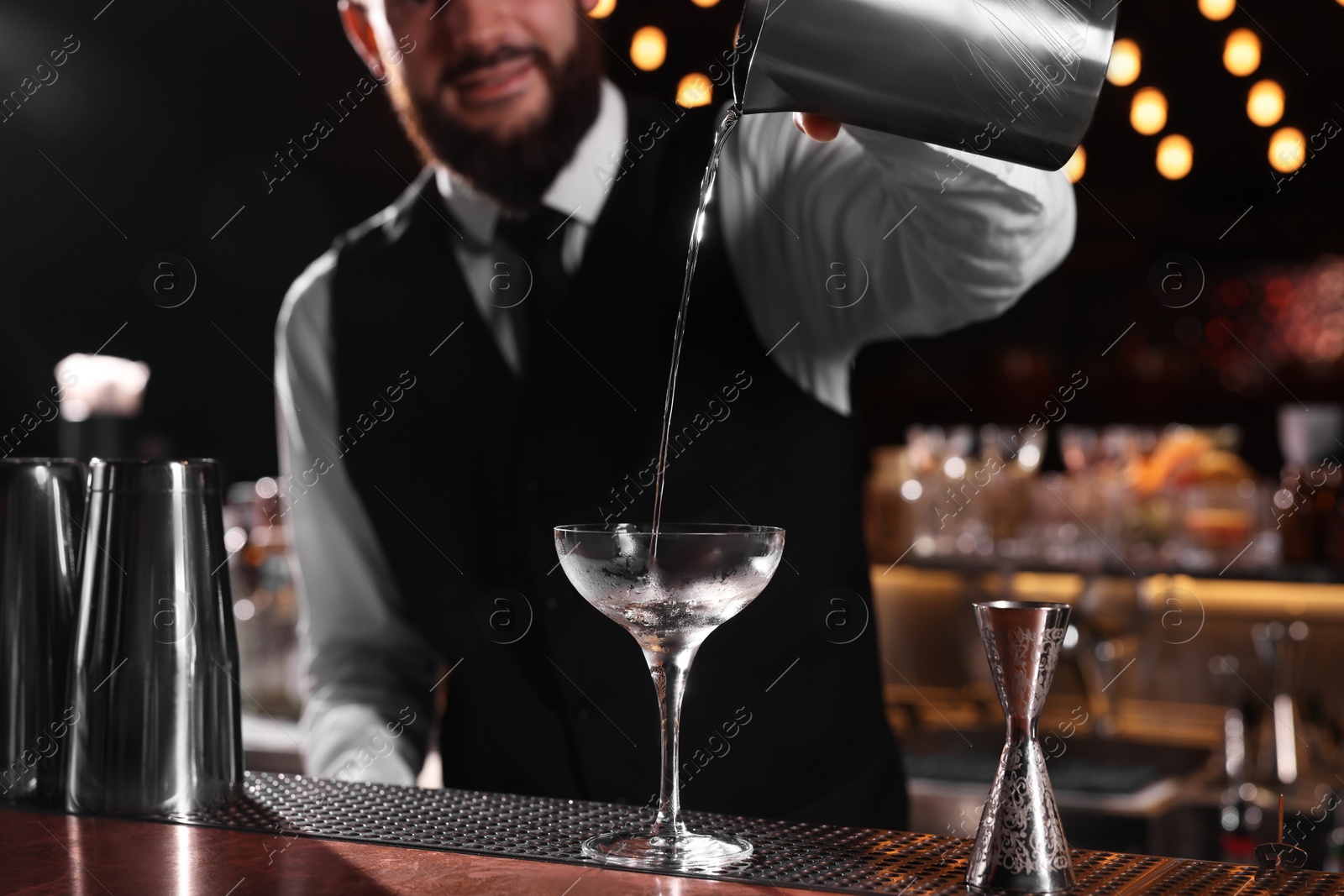 Photo of Bartender preparing fresh Martini cocktail at bar counter, closeup