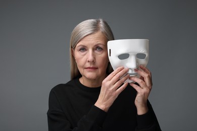 Photo of Multiple personality concept. Woman with mask on gray background