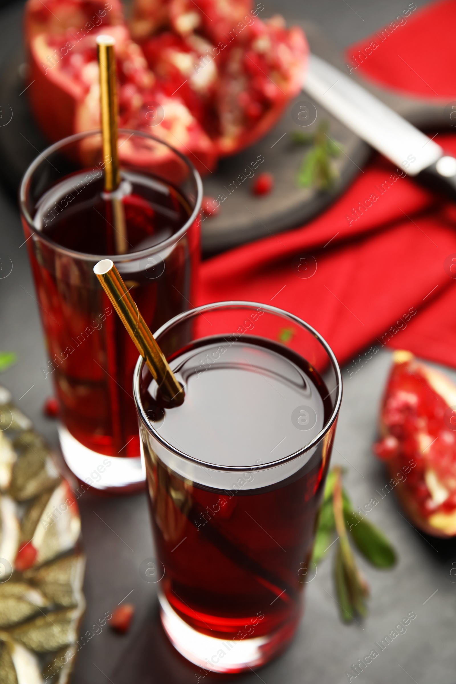 Photo of Pomegranate juice and fresh fruits on black table