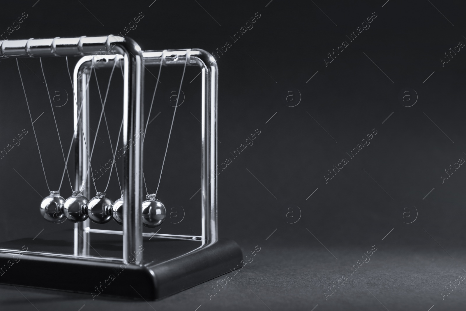 Photo of Newton's cradle on dark background, space for text. Physics law of energy conservation