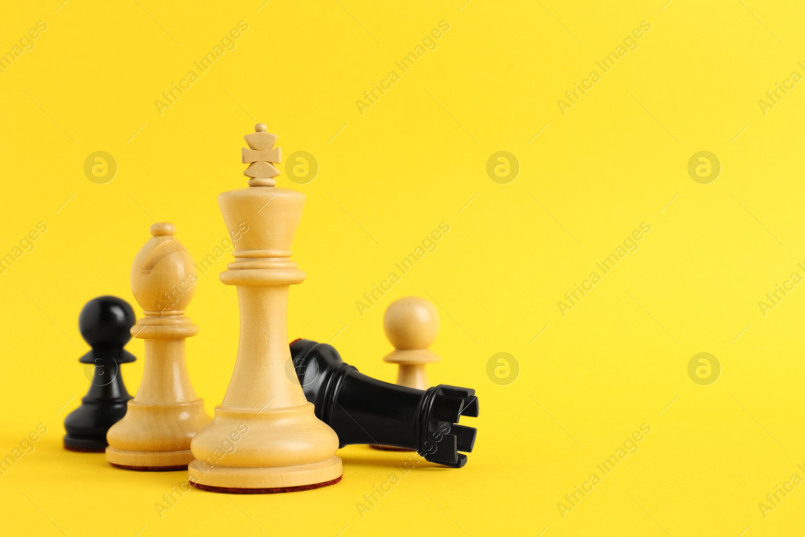 Photo of Different chess pieces on yellow background. Space for text