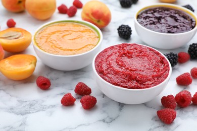 Photo of Different puree in bowls and fresh ingredients on white marble table