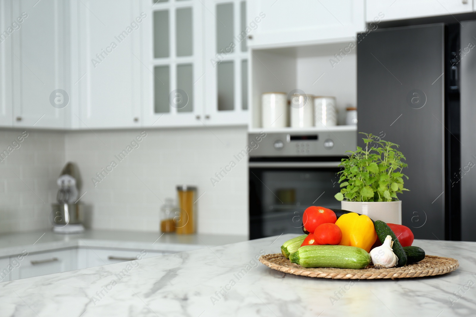 Photo of Different fresh vegetables on white table in modern kitchen. Space for text